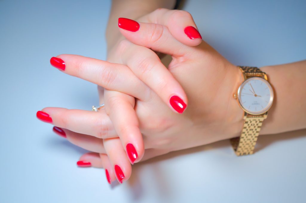 woman's hands crossing fingers wearing gold watch